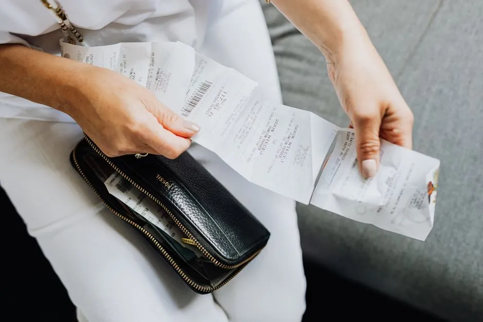 A shopper sorting through a handful of grocery store receipts pulled from a wallet